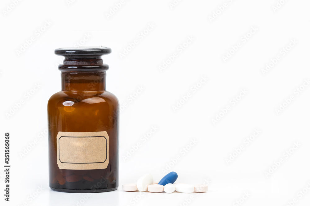 Medicamentos en pastillas y un frasco medicinal antiguo de cristal sobre fondo blanco asilado. Vista de frente. Copy space. Concepto: Salud Medicina Medicamentos en pastillas y un frasco medicinal antiguo de cristal sobre fondo blanco asilado. Vista de frente. Copy space. Concepto: Salud Medicina