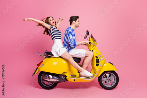 Profile side view portrait of his he her she nice attractive carefree cheerful cheery couple riding moped spending weekend vacation journey having fun isolated on pink pastel color background