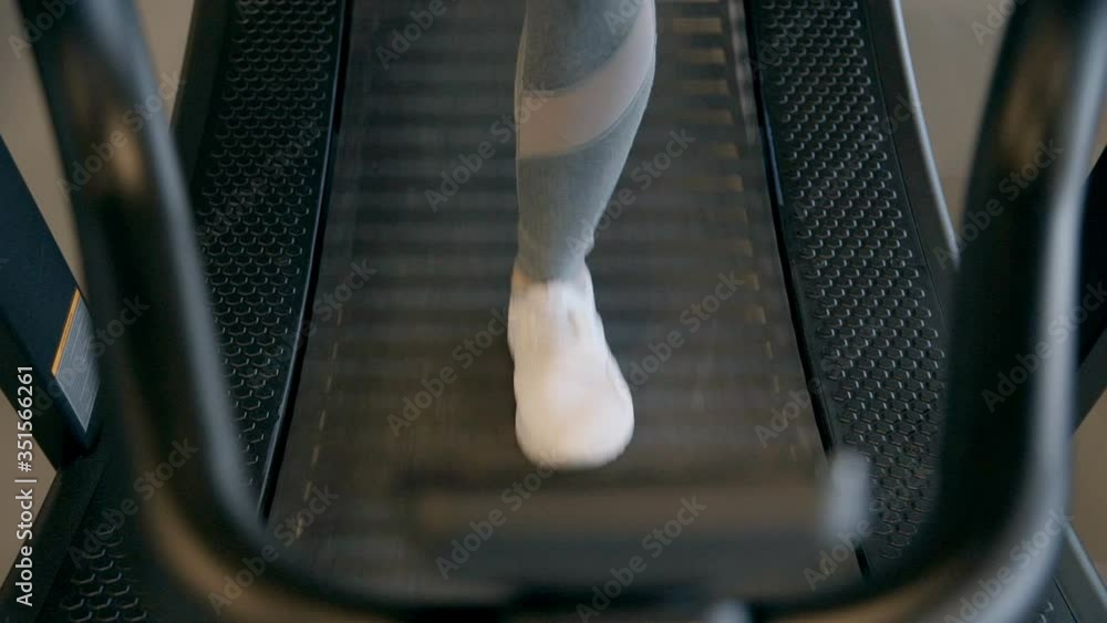 feet of woman are moving on treadmill in gym, in sporty sneakers closeup. Female legs running on treadmill in gym. woman exercising cardio. girl in trendy fitness sportswear. healthy lifestyle feet of woman are moving on treadmill in gym, in sporty sneakers closeup. Female legs running on treadmill in gym. woman exercising cardio. girl in trendy fitness sportswear. healthy lifestyle