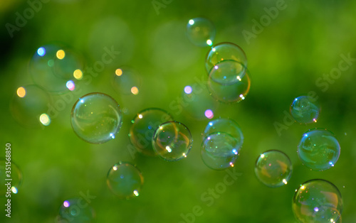 soap bubbles fly on a blurry green background. Concept - the Phantom of Hopes
