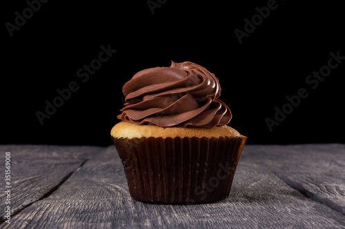 Chocolate cupcake with cocoa butter cream on dark wood