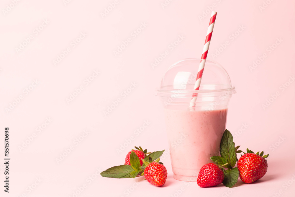 Glass of fresh strawberry milkshake, smoothie and fresh strawberries on pink, white and wooden background. Healthy food and drink concept. Glass of fresh strawberry milkshake, smoothie and fresh strawberries on pink, white and wooden background. Healthy food and drink concept.