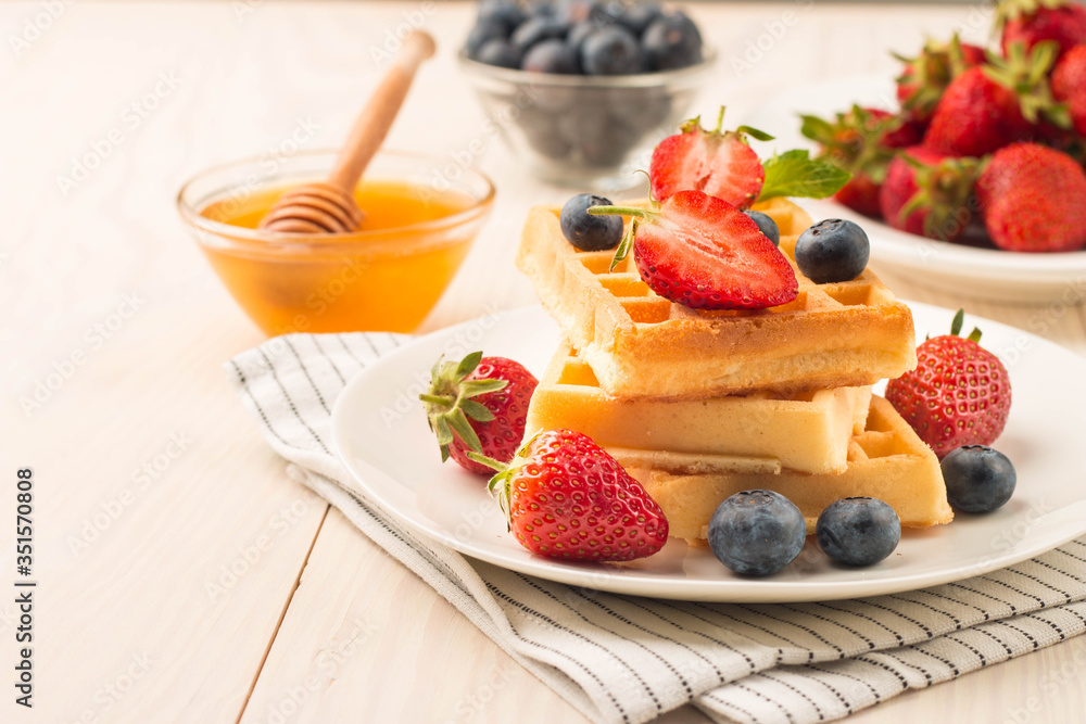 Fresh homemade food of berry Belgian waffles with honey, chocolate, strawberry, blueberry, maple syrup and cream. Healthy dessert breakfast concept with juice Fresh homemade food of berry Belgian waffles with honey, chocolate, strawberry, blueberry, maple syrup and cream. Healthy dessert breakfast concept with juice