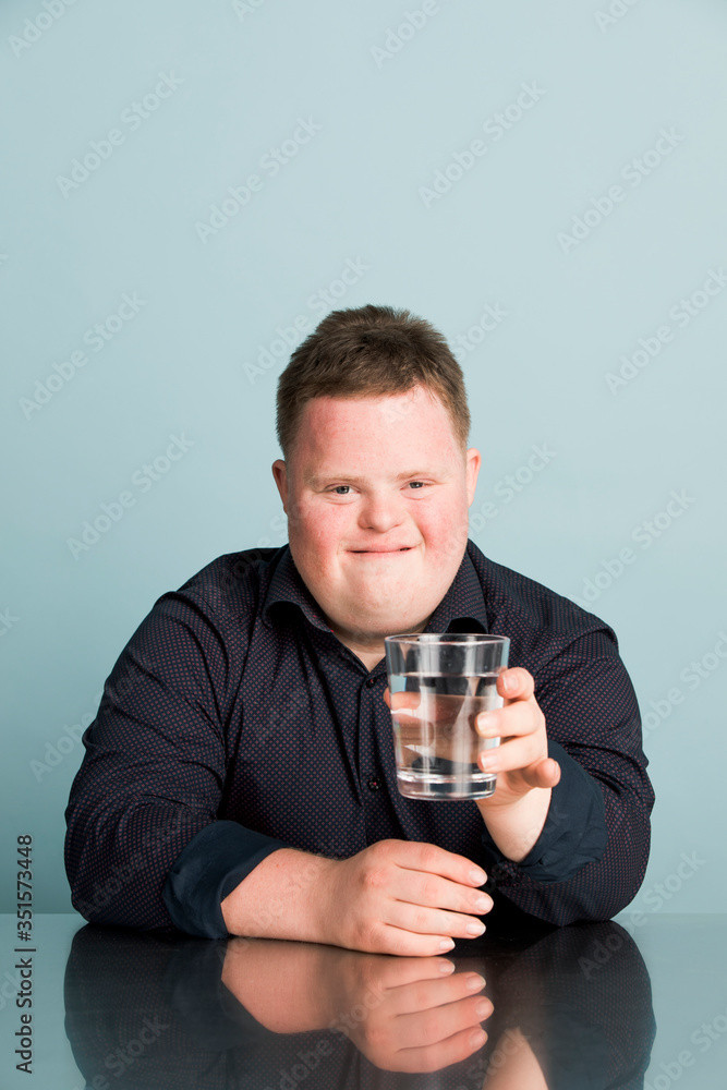 Cute boy with down syndrome holding a glass of water Cute boy with down syndrome holding a glass of water