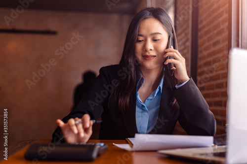 Happy usinesswoman use mobile phone and calculator in the office. photo