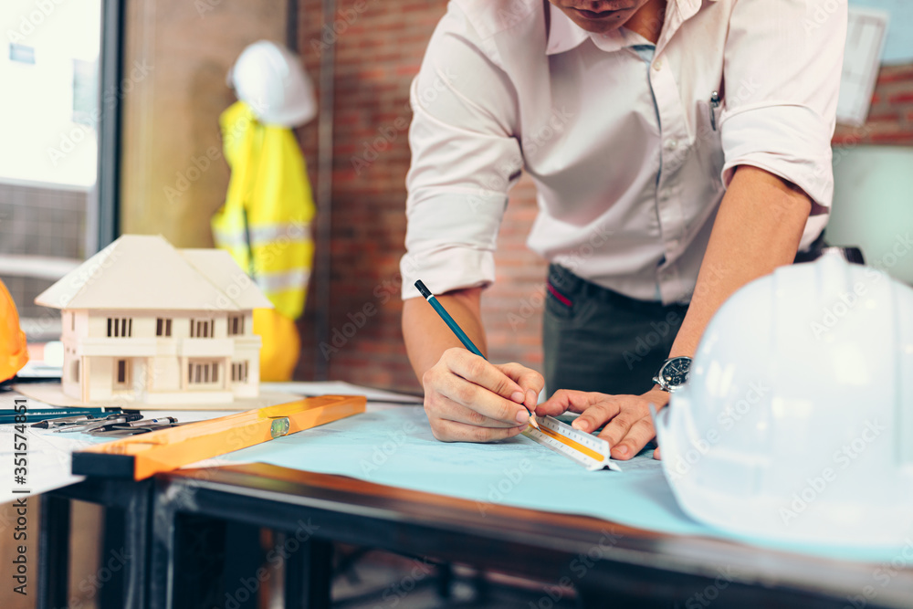 engineers holding a pen pointing to a building and drawing outlay construction plan as guide for builders with details. Engineer design and writing blueprint. engineers holding a pen pointing to a building and drawing outlay construction plan as guide for builders with details. Engineer design and writing blueprint.