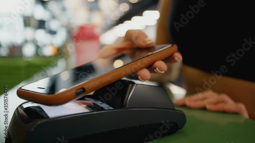 Mobile NFC payment for order in gym cafe. Hand of woman customer paying through mobile phone over pos terminal. money transfer through smartphone app. Apple pay concept