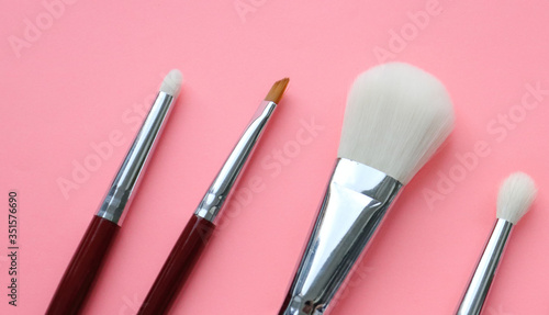 Wooden eye makeup brushes with natural white nap. A set of brushes for applying makeup, foundation, powder, blending eyeshadows, on a pink background. Brushes on a pink background