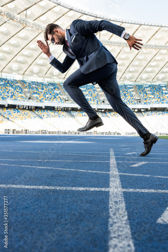 side view of young businessman in suit running at stadium