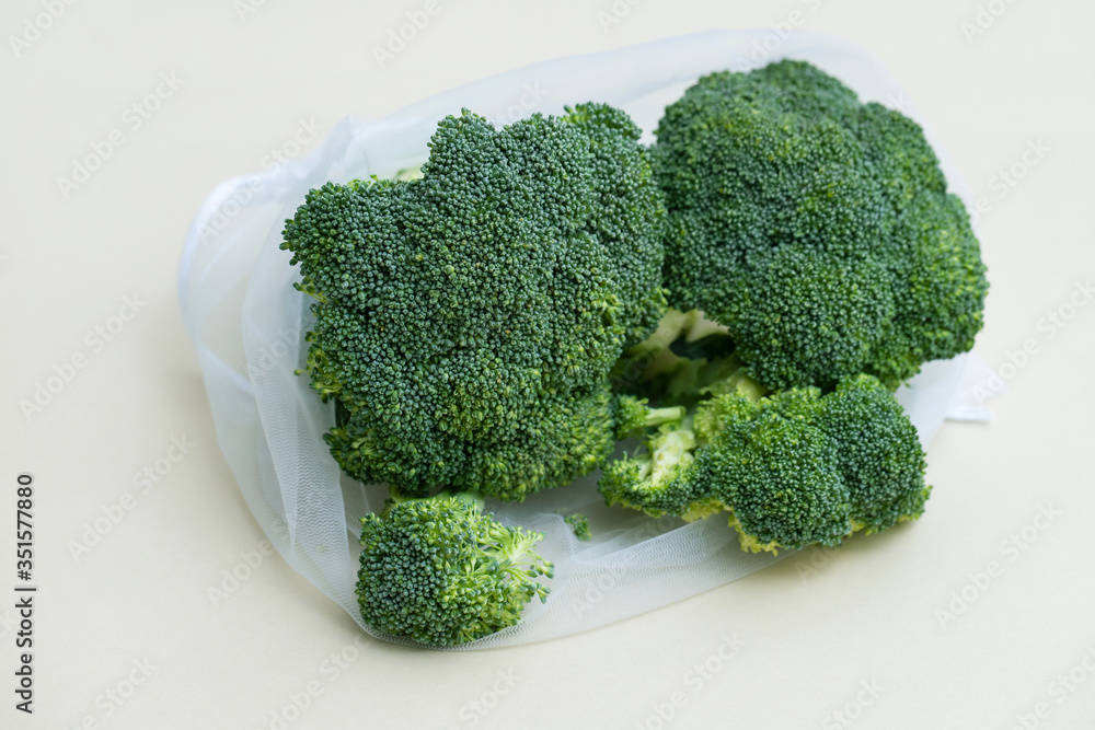 fresh broccoli with reusable bag on gray background fresh broccoli with reusable bag on gray background