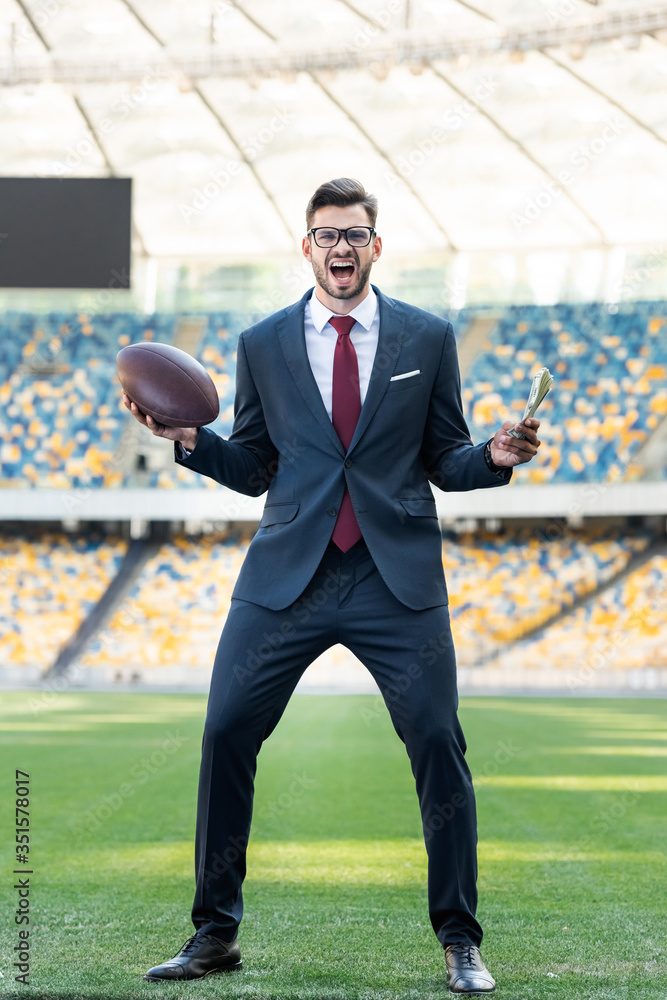 young businessman in suit and glasses with rugby ball yelling at stadium young businessman in suit and glasses with rugby ball yelling at stadium