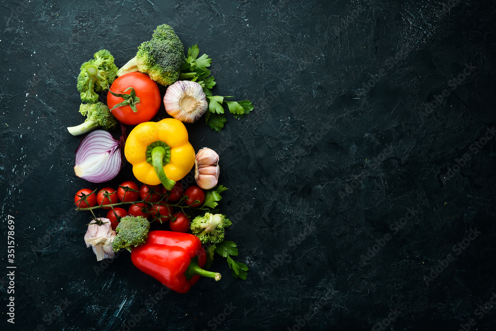 Ripe vegetables. Fresh vegetables on black stone background. Tropical fruits. Top view. Free space for your text.