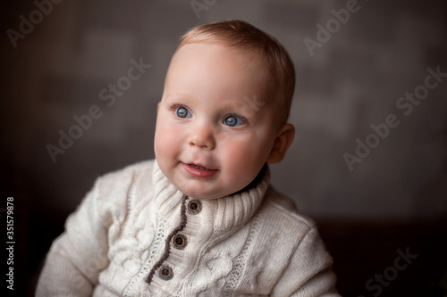 portrait of a little smiling boy in white sweater