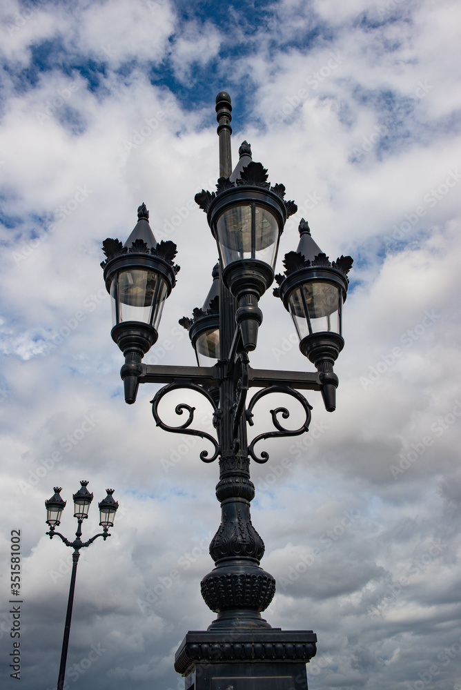 Looking up at street lights of Bordeaux, dark cloudy skies background