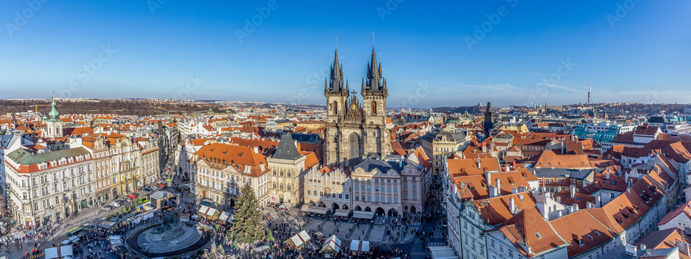 Old Town of Prague, Czech Republic. View on Tyn Church and Jan Hus Memorial on the square as seen from Old Town City Hall during Christmas market. Blue sunny sky