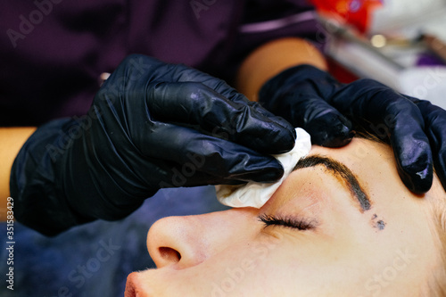 Eyebrow tattoo. Eyebrow coloring. Woman applying brow tint with makeup brush closeup.