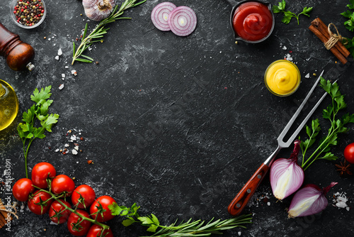 Black stone cooking background. Spices and vegetables. Top view. Free space for your text. photo