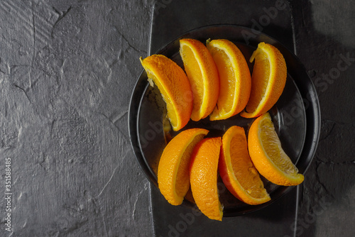 fresh orange slices on smooth black plates and cutting Board and on a textured graphite background