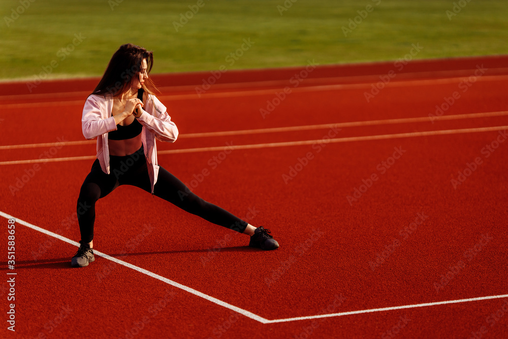 Beautiful fitness woman doing stretching workout before running on the stadium. Beautiful fitness woman doing stretching workout before running on the stadium.