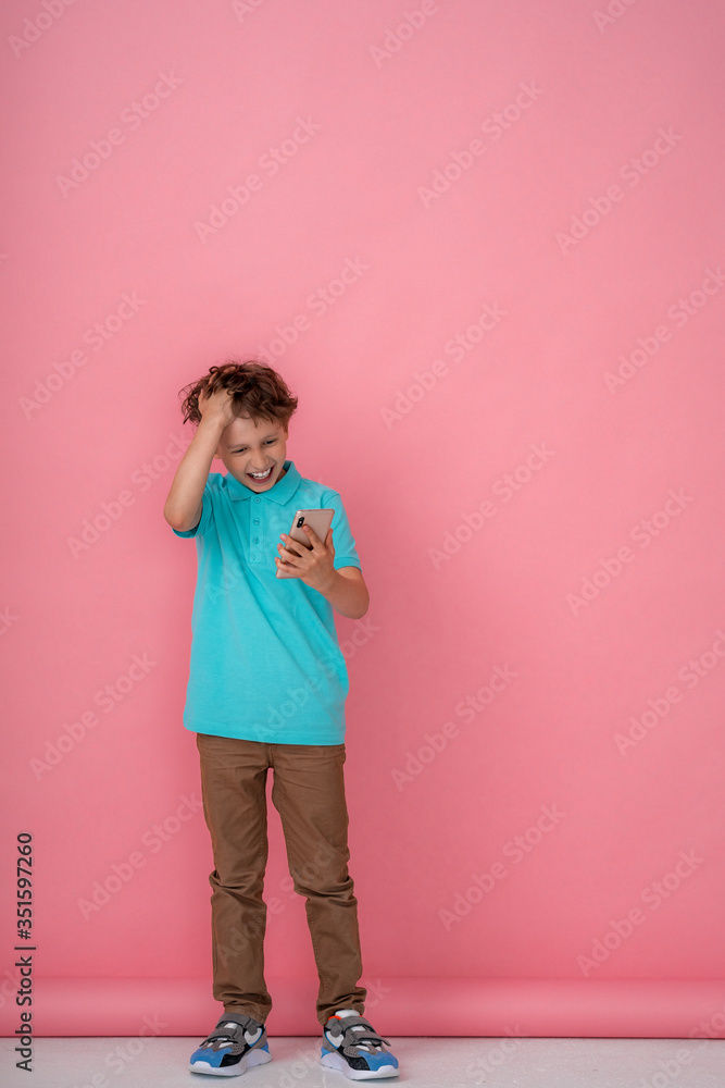 happy boy holding a smartphone on a pink background happy boy holding a smartphone on a pink background