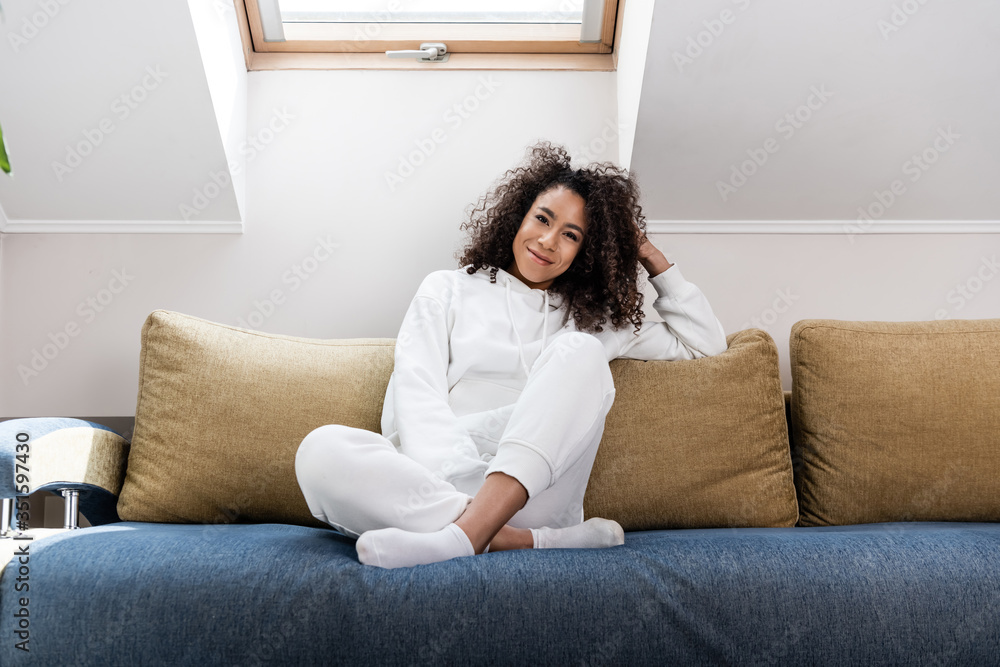 young african american woman smiling while sitting on sofa young african american woman smiling while sitting on sofa