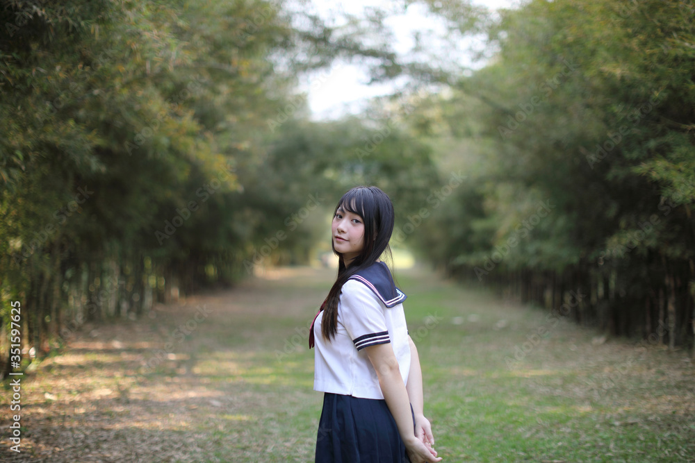 Portrait of beautiful Asian japanese high school girl uniform looking with bamboo forest background