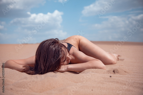 Beautiful girl in black swimsuit in the desert