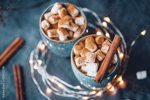 Hot chocolate with marshmallow and cinnamon in blue ceramic cups on a table. The concept of cosy holidays and New Year.