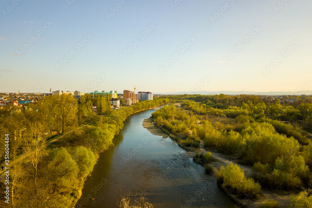 Aerial view of Ivano-Frankivsk city, Ukraine with Bystrytsia river and tall residential buildings under construction in distance.