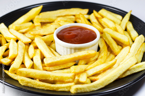 fries on the plate with ketchup  on the black background, studio shoot.