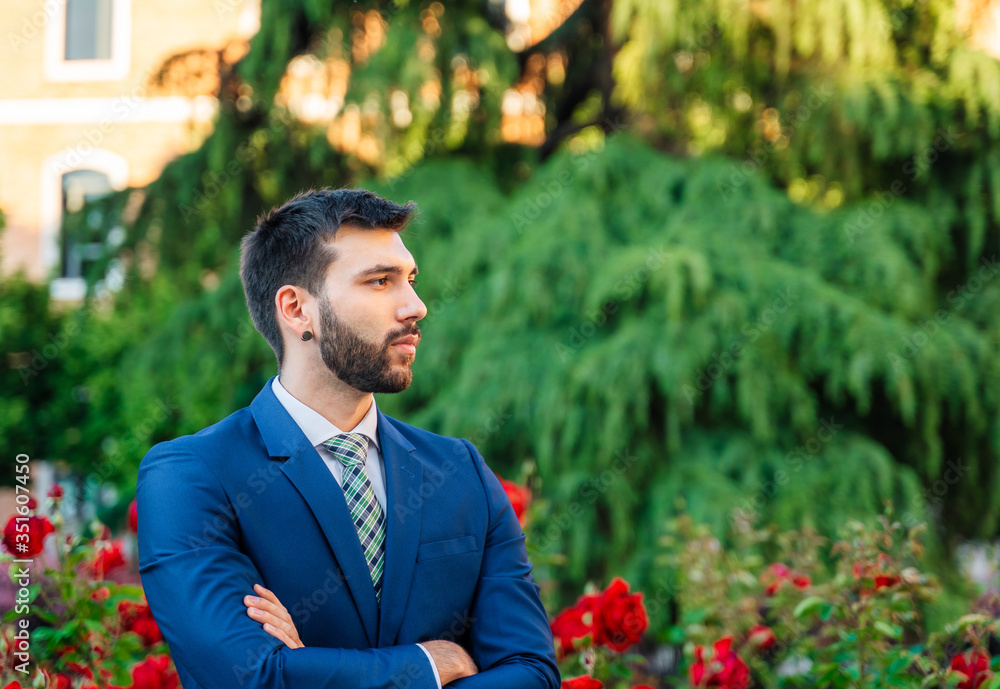 Young attractive business man with blue suit and tie in outdoor park Young attractive business man with blue suit and tie in outdoor park