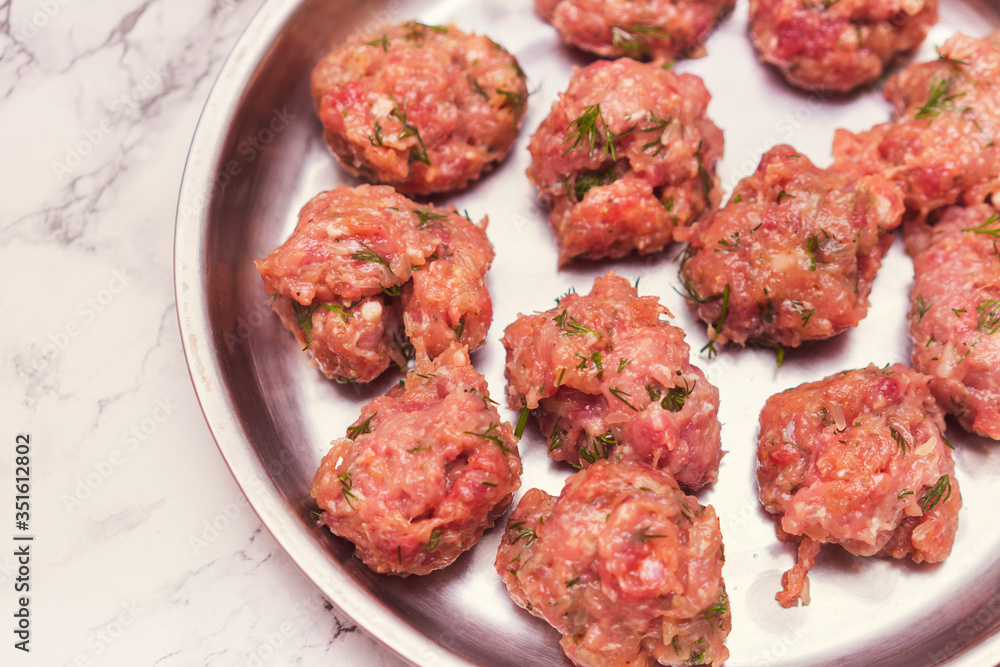 Prepared raw lumps of minced meat on a metal tray Prepared raw lumps of minced meat on a metal tray