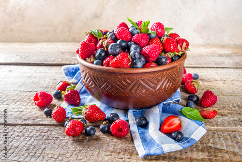 Raw Organic Assorted Various Fresh Berries with Blueberries Raspberries and Strawberries on rustic wooden background photo