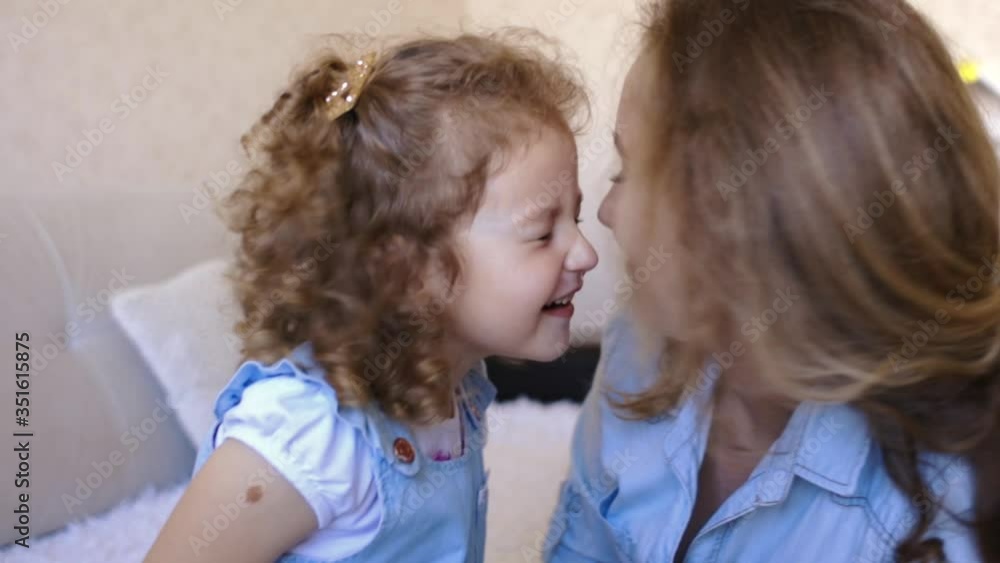 pretty caucasian blonde Mother and little curly hair daughter make eskimo kiss at home pretty caucasian blonde Mother and little curly hair daughter make eskimo kiss at home