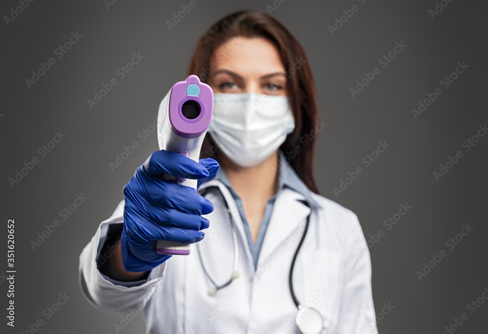 Female doctor measuring temperature with infrared thermometer Female doctor measuring temperature with infrared thermometer