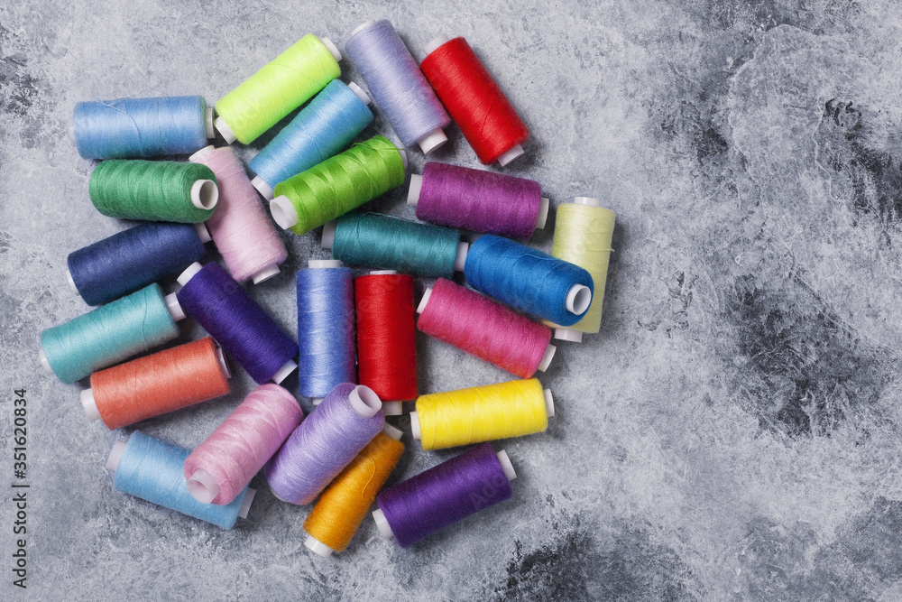 Colorful threads on bobbins, sewing set.On gray concrete background. Place for text. Colorful threads on bobbins, sewing set.On gray concrete background. Place for text.