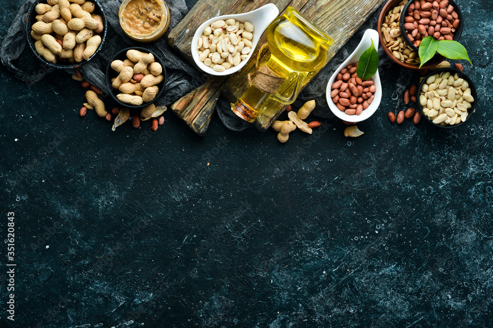 Peanut oil is cold pressed. Peanuts on a black stone background. Top view