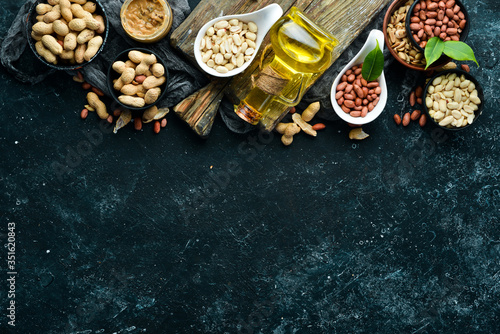 Peanut oil is cold pressed. Peanuts on a black stone background. Top view
