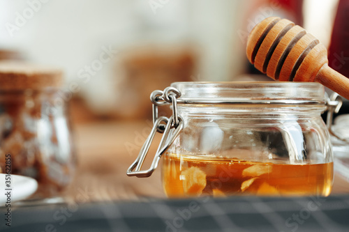 Glass jar of honey on wooden kitchen table