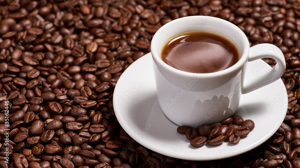 A cup of coffee, stands on coffee beans. A cup of coffee, stands on coffee beans.