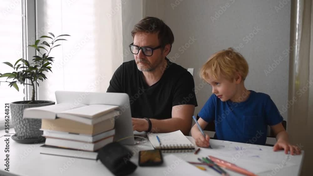 Man working from home with laptop during quarantine. Home office and parenthood at same time. Preschooler child drawing while parent freelancer making job. Difficulties with kids during isolation Man working from home with laptop during quarantine. Home office and parenthood at same time. Preschooler child drawing while parent freelancer making job. Difficulties with kids during isolation