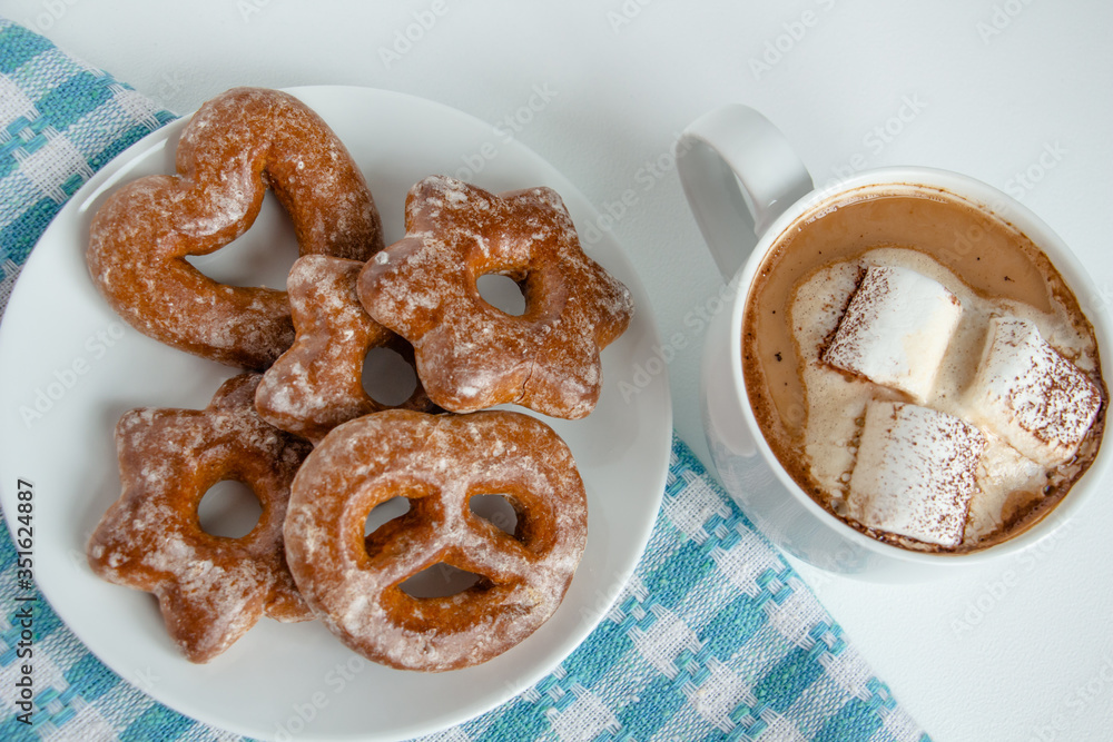 fragrant gingerbread cookies on a white plate with a cup of warm cocoa or coffee with marshmallow, sprinkled with chocolate, white background, blue napkin, delicious dessert, feeling of comfort fragrant gingerbread cookies on a white plate with a cup of warm cocoa or coffee with marshmallow, sprinkled with chocolate, white background, blue napkin, delicious dessert, feeling of comfort