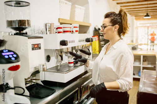 Waiter working with a professional coffee machine, behind a restaurant bar. Inside