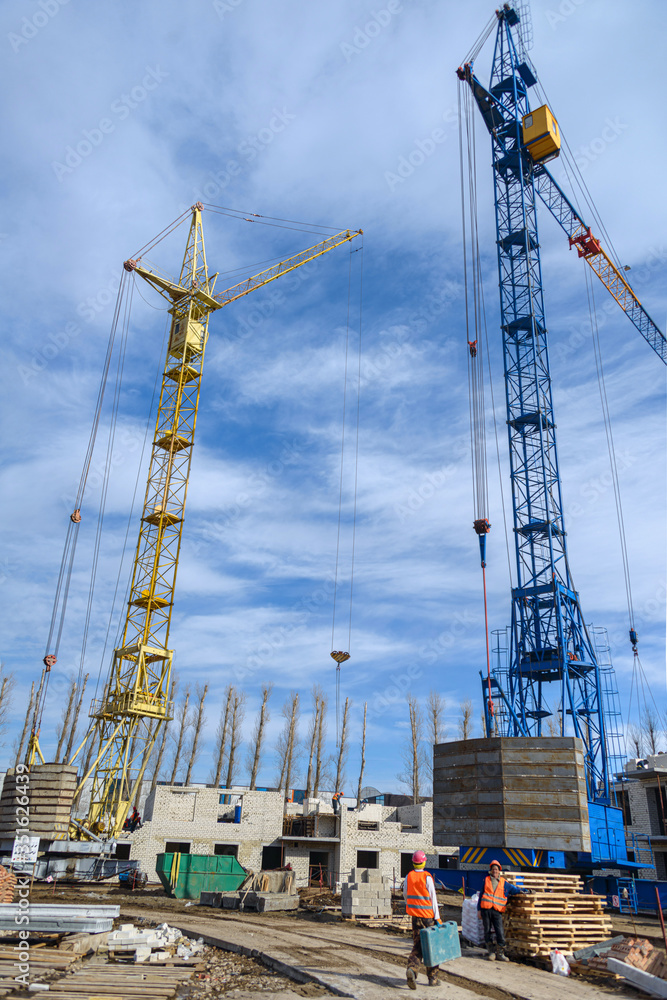 Photos of high-rise construction cranes and an unfinished house against a blue sky. Photographed on a wide angle lens