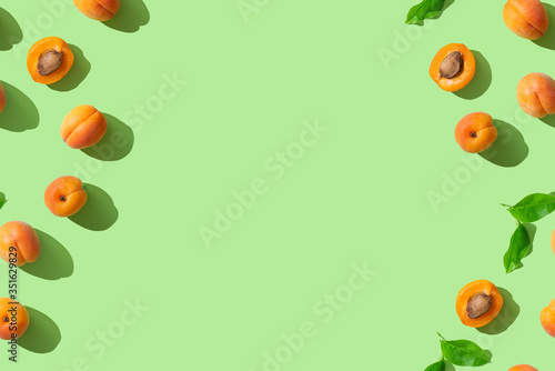 Trendy summer pattern with ripe apricots on green background. Minimal summer concept. Wallpaper, sale, discount, natural cosmetics banner background. Copy space