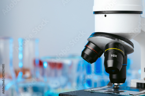 Scientific laboratory with microscope and test tubes with samples, close up photo