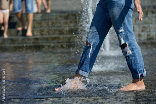 Photography Shoeless girl feet playing with fountain water jets at square