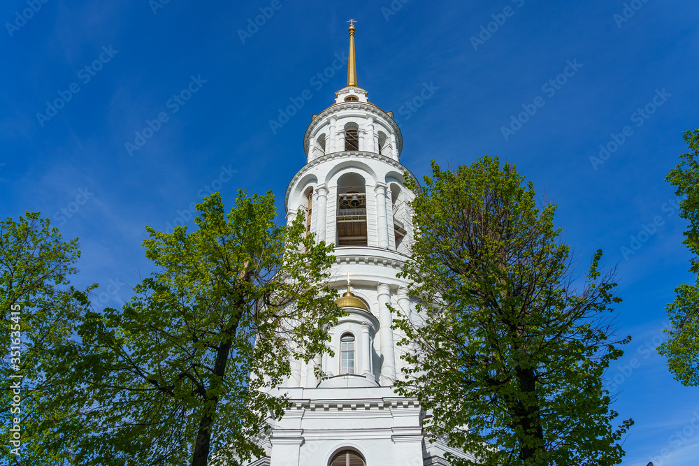 bell tower against a blue sky, in the foreground trees