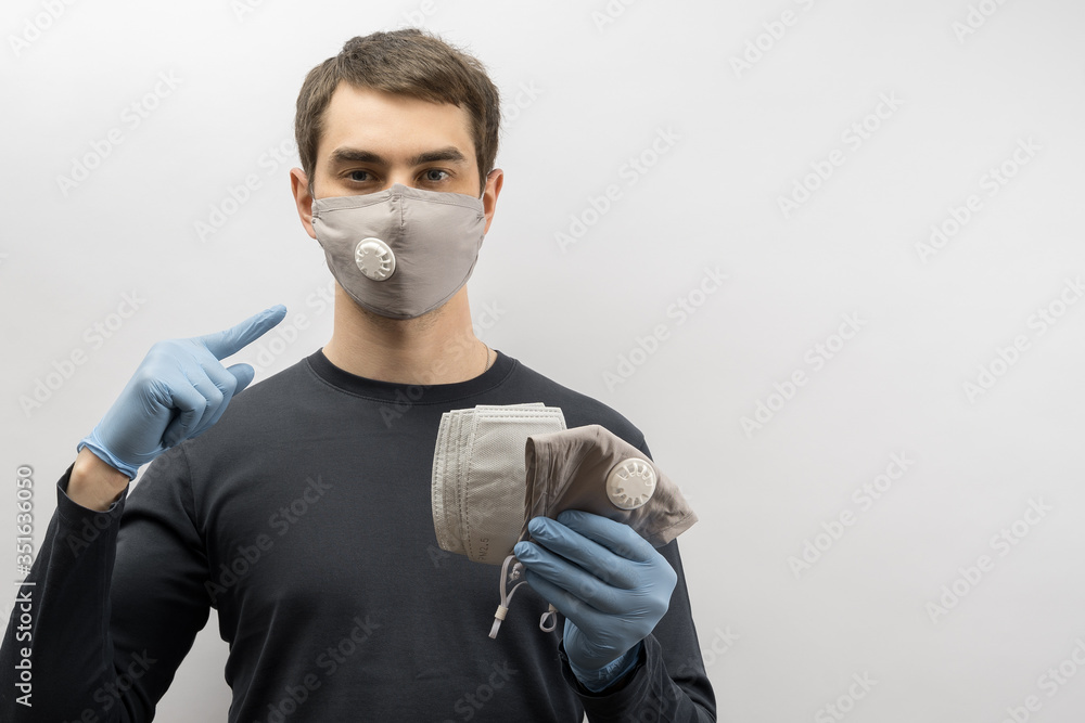 Young european man wearing mask against the corona virus and thumbs up covid 19 man wearing reusable surgical mask to prevent from virus white\grey background Corona virus pandemic funny fun Young european man wearing mask against the corona virus and thumbs up covid 19 man wearing reusable surgical mask to prevent from virus white\grey background Corona virus pandemic funny fun