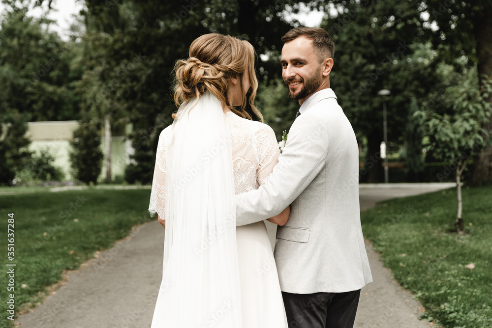bride and groom hold hands and look back,stylish wedding couple for a walk in the park,bride and groom with their backs to the camera,wedding day of a young couple bride and groom hold hands and look back,stylish wedding couple for a walk in the park,bride and groom with their backs to the camera,wedding day of a young couple